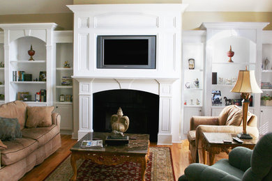 チャールストンにある中くらいなトラディショナルスタイルのおしゃれなLDK (ベージュの壁、無垢フローリング、標準型暖炉、漆喰の暖炉まわり、壁掛け型テレビ、茶色い床) の写真