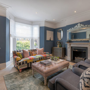 Classic open plan living room in London with blue walls, light hardwood flooring, a standard fireplace and beige floors.