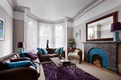 На фото: гостиная комната в стиле фьюжн с серыми стенами, ковровым покрытием, стандартным камином и фасадом камина из камня с