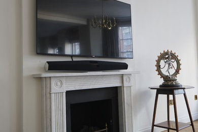ロンドンにある高級な広いトラディショナルスタイルのおしゃれなリビング (白い壁、無垢フローリング、標準型暖炉、石材の暖炉まわり、壁掛け型テレビ) の写真