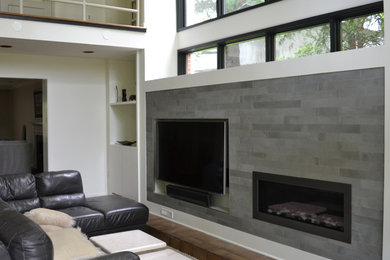 Minimalist living room photo in DC Metro with a bar, gray walls, a standard fireplace, a tile fireplace and a media wall
