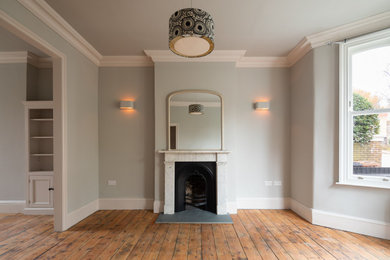 ロンドンにあるお手頃価格の広いトラディショナルスタイルのおしゃれなリビング (グレーの壁、無垢フローリング、標準型暖炉、石材の暖炉まわり、テレビなし) の写真