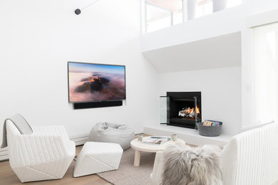 Imagen de salón abierto escandinavo con paredes blancas, suelo de madera en tonos medios, todas las chimeneas, televisor colgado en la pared y suelo marrón
