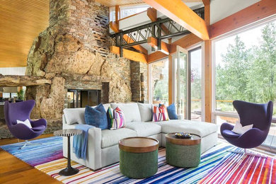 Inspiration for a rustic medium tone wood floor living room remodel in Denver with a two-sided fireplace and a stone fireplace