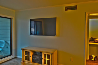 Inredning av ett maritimt vardagsrum, med mellanmörkt trägolv och en väggmonterad TV