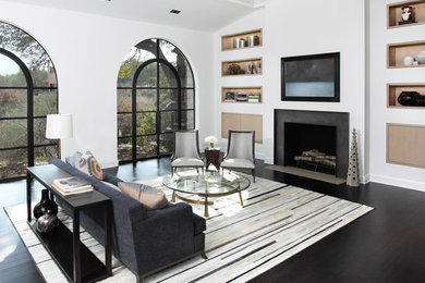 Example of a large trendy open concept and formal dark wood floor and black floor living room design in Austin with white walls, a standard fireplace, a concrete fireplace and a media wall