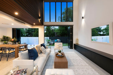 Diseño de salón abierto actual de tamaño medio con paredes blancas, suelo de cemento, televisor colgado en la pared y suelo gris