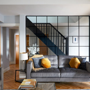 This is an example of a medium sized contemporary enclosed living room in London with grey walls, medium hardwood flooring, a vaulted ceiling and brown floors.