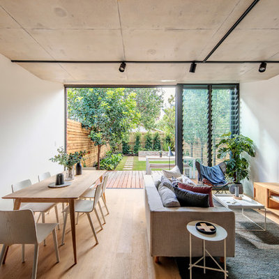 Trendy open concept medium tone wood floor and brown floor living room photo in Sydney with white walls and a tv stand