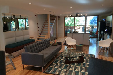 Diseño de salón para visitas abierto actual de tamaño medio sin chimenea y televisor con paredes blancas, suelo de madera clara y suelo marrón