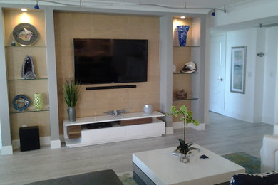 This is an example of a medium sized contemporary open plan living room in Miami with white walls, light hardwood flooring and a wall mounted tv.