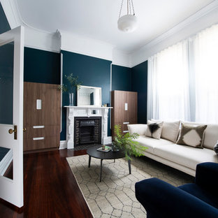 This is an example of a mid-sized transitional living room with dark hardwood floors, a standard fireplace, a tile fireplace surround, blue walls, a concealed tv and brown floor.