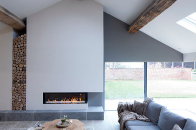 チェシャーにある高級な広いコンテンポラリースタイルのおしゃれな応接間 (白い壁、ライムストーンの床、横長型暖炉、漆喰の暖炉まわり) の写真