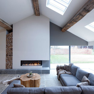 Idee per un grande soggiorno design con pareti bianche, pavimento in pietra calcarea, camino lineare Ribbon, cornice del camino in intonaco e sala formale