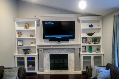 オタワにあるトランジショナルスタイルのおしゃれなリビング (白い壁、濃色無垢フローリング、標準型暖炉、タイルの暖炉まわり、壁掛け型テレビ) の写真