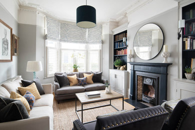 Example of an ornate living room library design in London with gray walls, a wood stove and a tile fireplace