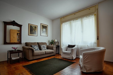 Imagen de salón cerrado bohemio pequeño sin chimenea con paredes blancas, suelo de madera oscura y suelo marrón