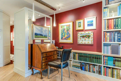 Imagen de biblioteca en casa abierta contemporánea de tamaño medio sin chimenea y televisor con paredes rojas, suelo de madera en tonos medios y suelo marrón