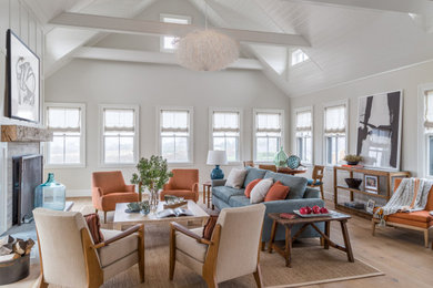 Example of a beach style medium tone wood floor, brown floor, shiplap ceiling and vaulted ceiling living room design in San Francisco with gray walls and a standard fireplace