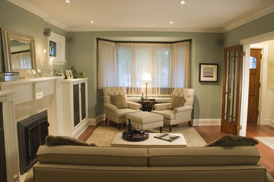 Пример оригинального дизайна: парадная, изолированная гостиная комната среднего размера в стиле неоклассика (современная классика) с зелеными стенами, паркетным полом среднего тона, стандартным камином и фасадом камина из металла без телевизора