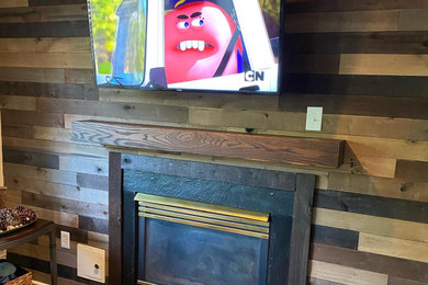 Modelo de salón campestre de tamaño medio con paredes beige, suelo laminado, todas las chimeneas, marco de chimenea de madera, televisor colgado en la pared, suelo marrón y madera