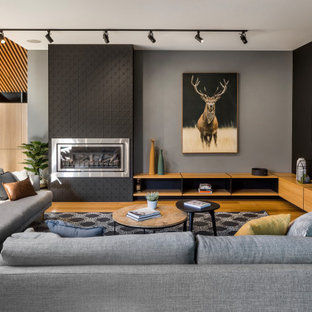 Design ideas for a mid-sized contemporary open concept living room in Melbourne with black walls, a ribbon fireplace, a metal fireplace surround, a wall-mounted tv, brown floor and medium hardwood floors.