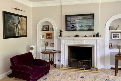 ハートフォードシャーにある高級な広いトラディショナルスタイルのおしゃれなリビング (ベージュの壁、無垢フローリング、標準型暖炉、石材の暖炉まわり、壁掛け型テレビ、茶色い床) の写真