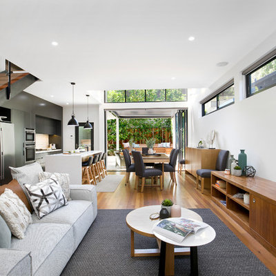 Example of a trendy open concept medium tone wood floor and brown floor living room design in Sydney with white walls, no fireplace and a wall-mounted tv