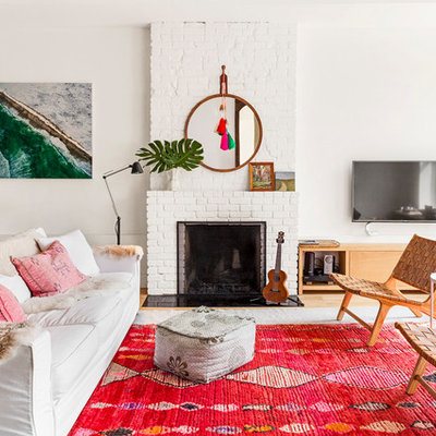 Living room - eclectic formal light wood floor and brown floor living room idea in New York with white walls, a standard fireplace, a brick fireplace and a wall-mounted tv