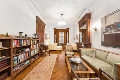 This is an example of a traditional enclosed living room in New York with white walls, medium hardwood flooring and brown floors.