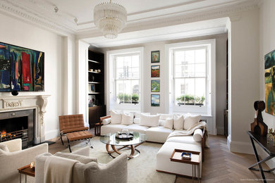 Design ideas for a large traditional formal open plan living room in London with white walls, medium hardwood flooring, a standard fireplace, a stone fireplace surround, a concealed tv and brown floors.