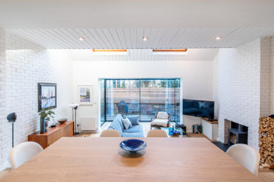 Ejemplo de salón escandinavo con paredes blancas, suelo de madera clara, estufa de leña y televisor colgado en la pared