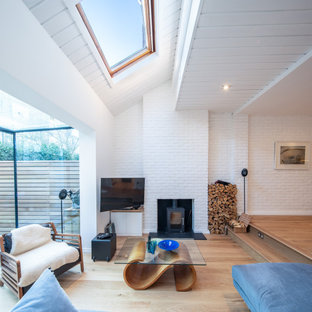 Danish light wood floor living room photo in London with white walls, a wood stove and a wall-mounted tv