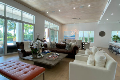 This is an example of a large modern formal open plan living room in Miami with white walls, light hardwood flooring, no fireplace, a wall mounted tv, grey floors and a wood ceiling.