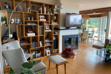 Example of a 1950s open concept laminate floor living room library design in San Francisco with white walls, a two-sided fireplace, a brick fireplace and a wall-mounted tv