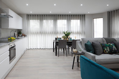 Medium sized contemporary open plan living room in London with grey walls, light hardwood flooring, no fireplace, a freestanding tv and grey floors.