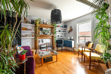 Small eclectic enclosed living room in Toronto with purple walls, medium hardwood flooring, a standard fireplace, a wooden fireplace surround, no tv and brown floors.