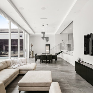 This is an example of a mid-sized contemporary open concept living room in Sydney with white walls, a wall-mounted tv and grey floor.
