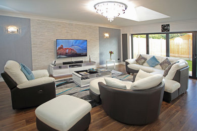 Foto de salón con barra de bar abierto contemporáneo extra grande con suelo de madera en tonos medios, televisor colgado en la pared y paredes multicolor