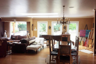 Foto de salón abierto ecléctico grande con paredes beige, suelo de madera clara, chimenea de esquina, marco de chimenea de yeso y televisor colgado en la pared