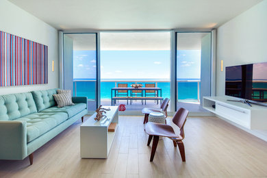 Ejemplo de salón actual con paredes azules, suelo de madera clara, televisor independiente y suelo beige