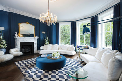 Стильный дизайн: огромная парадная, изолированная гостиная комната в стиле фьюжн с синими стенами, паркетным полом среднего тона, стандартным камином, фасадом камина из камня и коричневым полом без телевизора - последний тренд