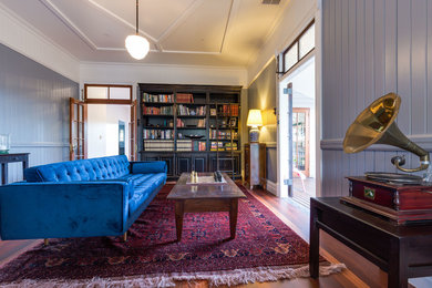 Foto de biblioteca en casa cerrada tradicional de tamaño medio sin chimenea y televisor con paredes azules y suelo de madera en tonos medios