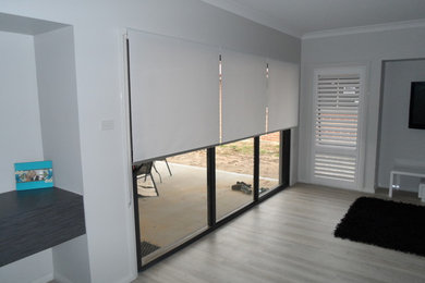 This is an example of a medium sized contemporary open plan living room in Newcastle - Maitland with white walls, light hardwood flooring and a wall mounted tv.