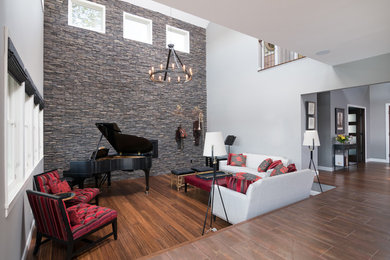 Idee per un grande soggiorno american style stile loft con sala della musica, pareti grigie, pavimento in bambù, camino classico, cornice del camino in pietra e pavimento marrone