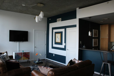 Diseño de salón con barra de bar abierto industrial pequeño sin chimenea con paredes azules, suelo de madera oscura y televisor colgado en la pared