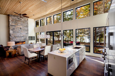 Example of a large arts and crafts open concept dark wood floor and brown floor living room design in Other with beige walls, a ribbon fireplace, a stone fireplace and a wall-mounted tv