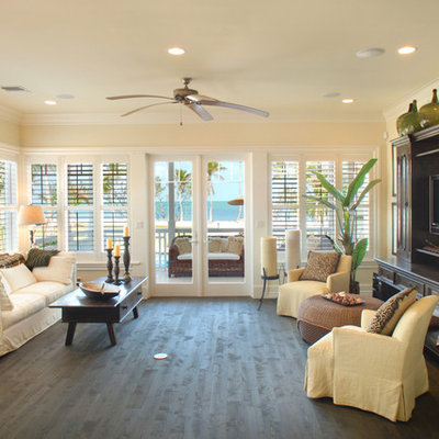 Example of a large island style open concept dark wood floor and brown floor living room design in Miami with beige walls and a concealed tv