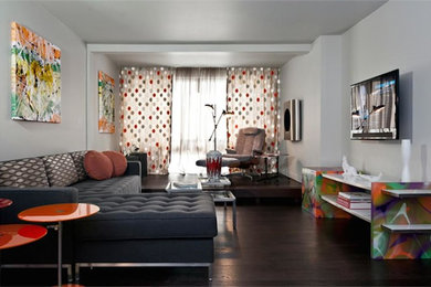Modelo de salón abierto contemporáneo de tamaño medio sin chimenea con paredes grises, suelo de madera oscura, televisor colgado en la pared y suelo marrón