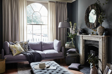 Inspiration pour un salon traditionnel de taille moyenne avec un mur gris, un sol en bois brun, une cheminée standard, un sol marron et un manteau de cheminée en pierre.
